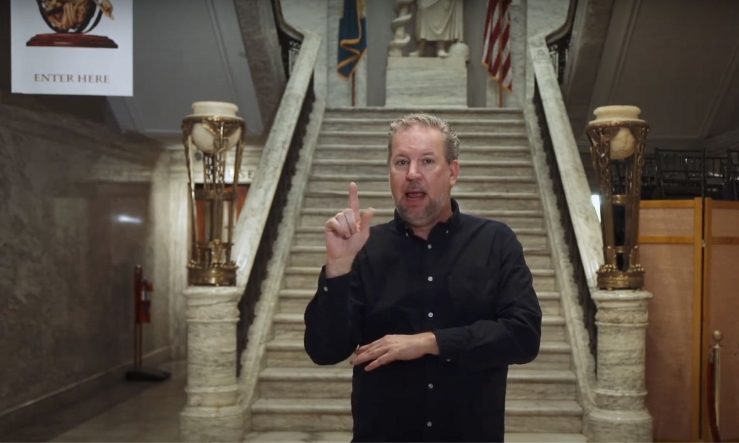 ASL interpreter in front of a marble staircase.
